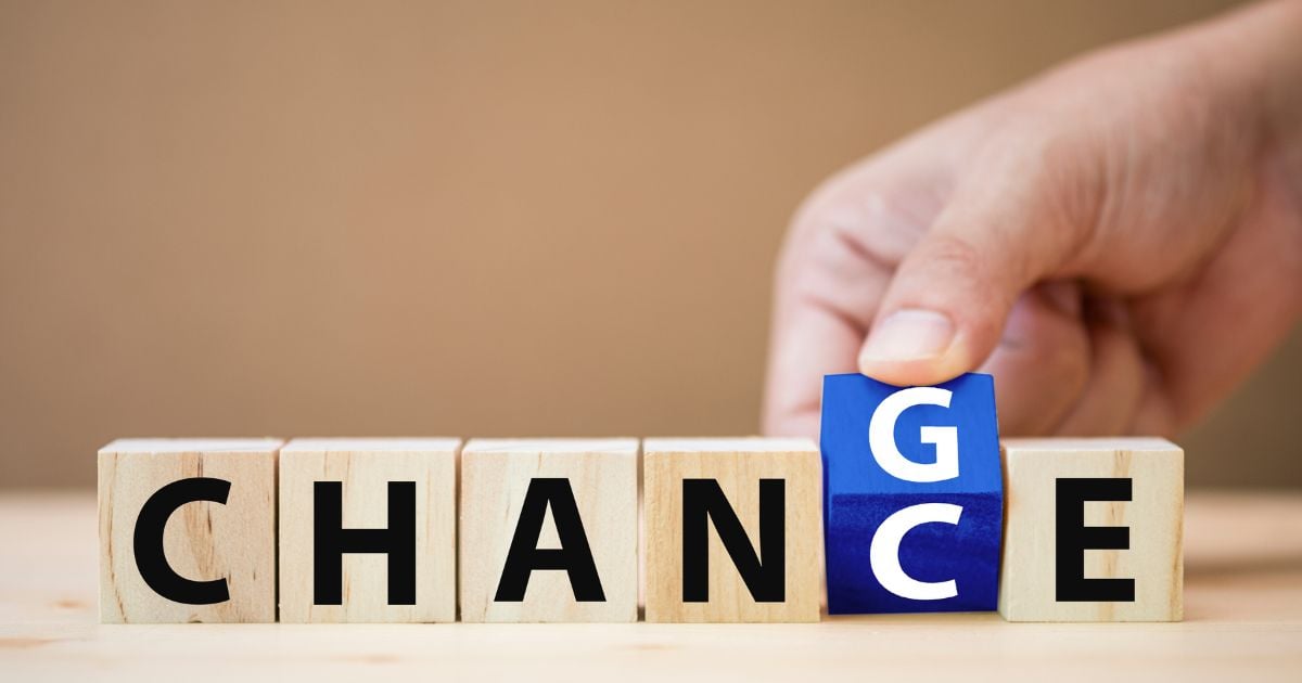 Hand flipping wooden cubes to change wording from change to chance