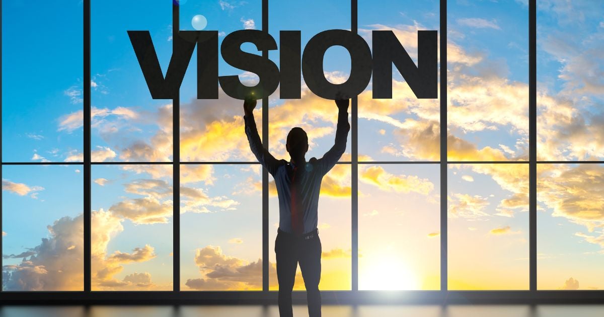 Silhouette of business man holding a vision sign in an office with a sunset background