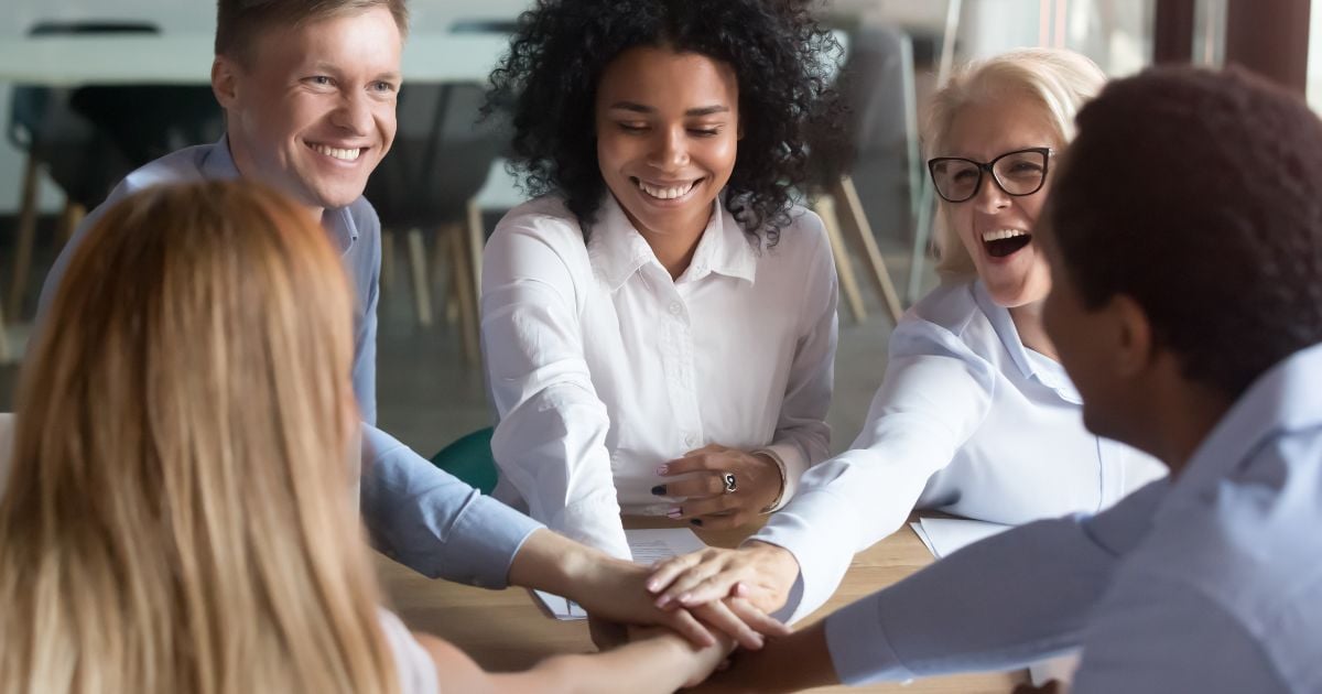 Multi-ethnic happy employees stacking hands in a pile for team building